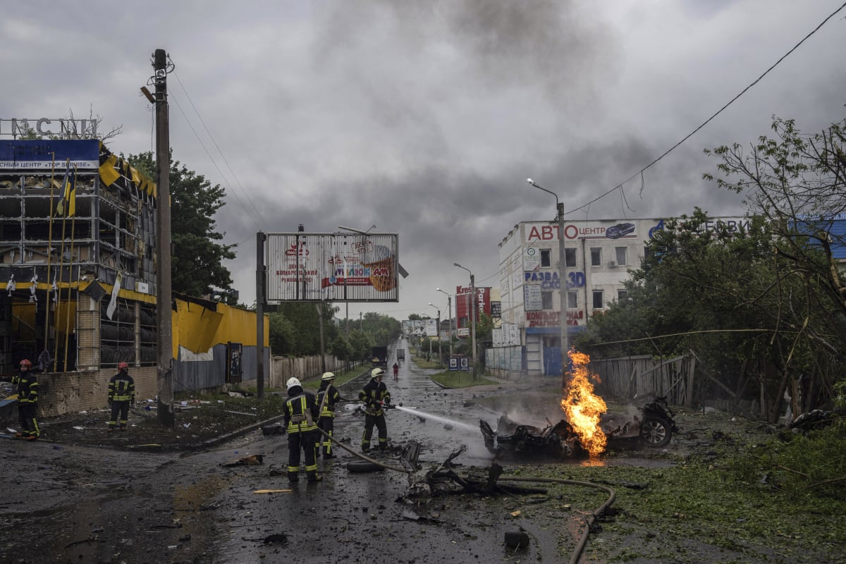 Hasiči likvidují požár vraku auta po ruském útoku na Charkov. 