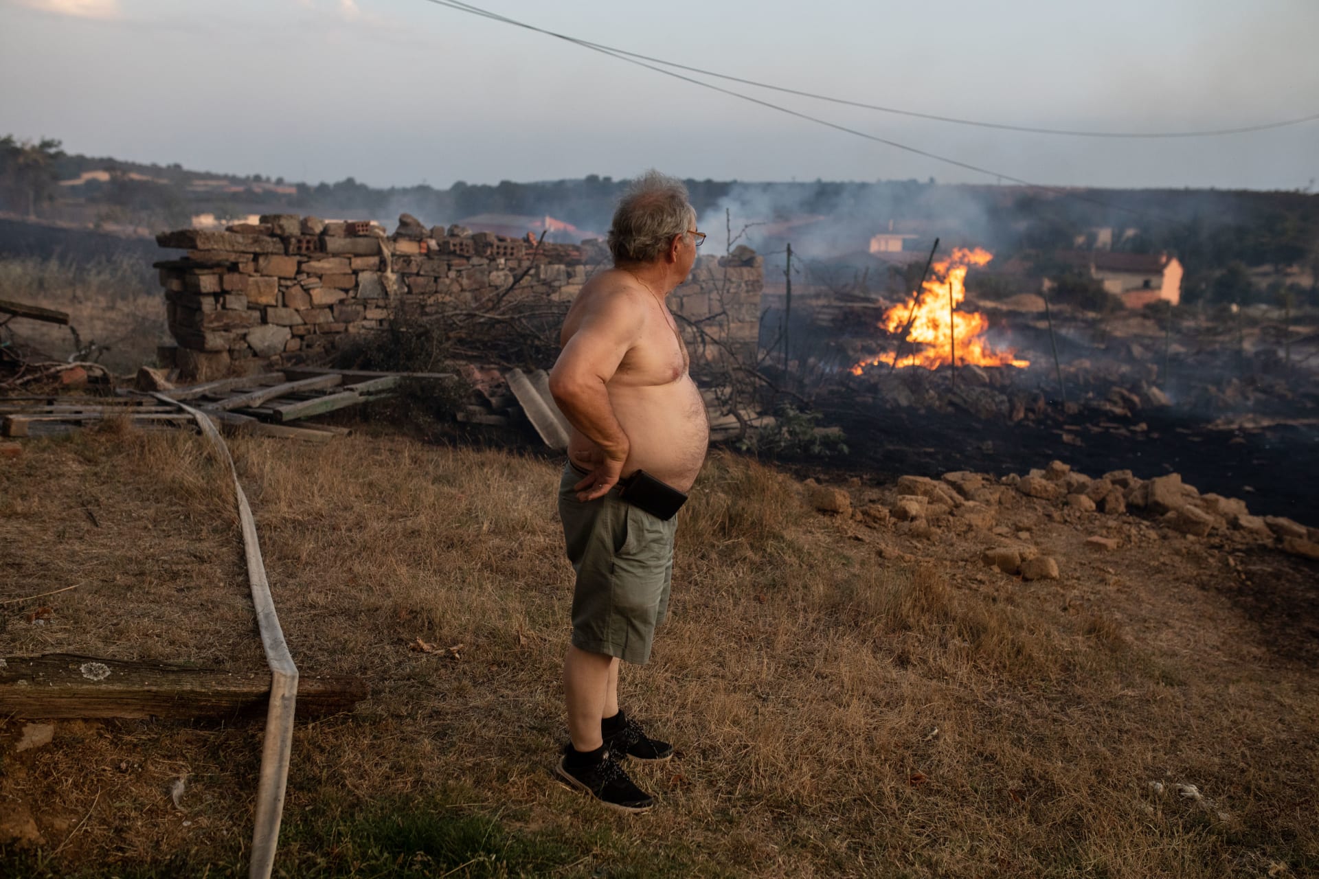 Muž sleduje plameny požáru Losacio 17. července 2022.