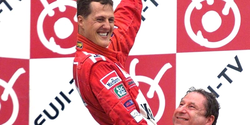 Ředitel stáje Ferrari Jean Todt (vpravo) zvedá při vyhlášení výsledků po Velké ceně Japonska 2000 v Suzuce vítěze, německého pilota Michaela Schumachera. 