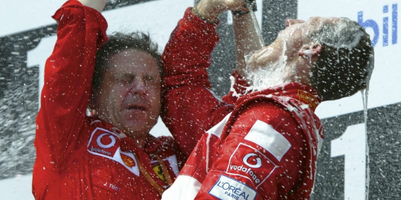 Německý pilot formule 1 Michael Schumacher (vlevo) pije za pomoci ředitele stáje Ferrari Jean Todt šampaňské po vítězství a zisku titulu mistra světa 2002 ve francouzském Magny Cours.