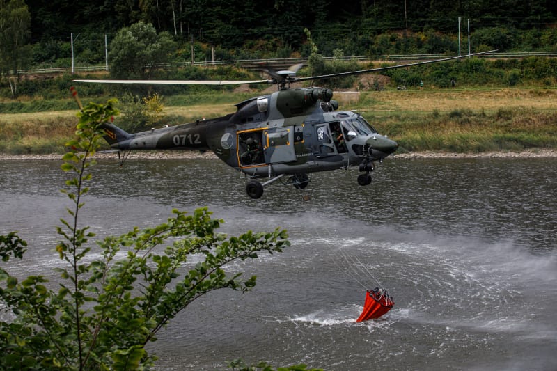 Do akce jsou zapojeny i vrtulníky, které oheň kropí vodou.
