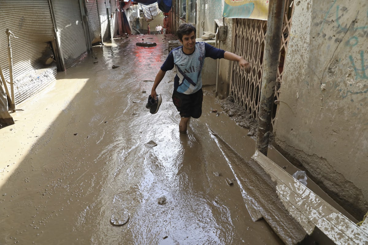 Muž se brodí v bahně po bleskových záplavách v severozápadní části Teheránu v Íránu, čtvrtek 28. července 2022. 