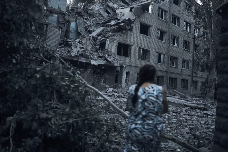 Žena pochází mezi troskami domu po ruském ostřelování města Mykolajiv