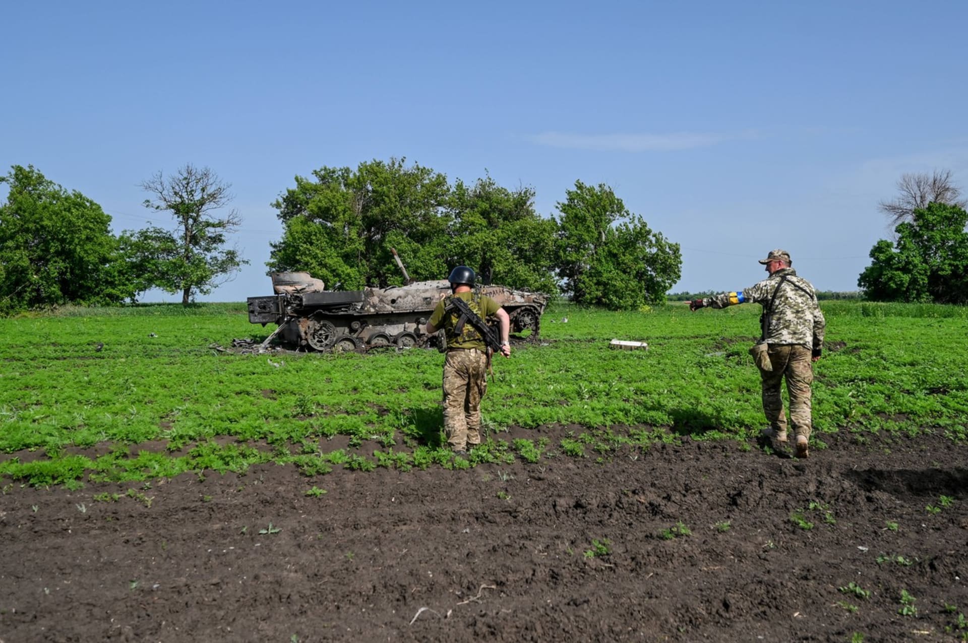 Ukrajinští vojáci stojí u zničeného ruského obrněnce.