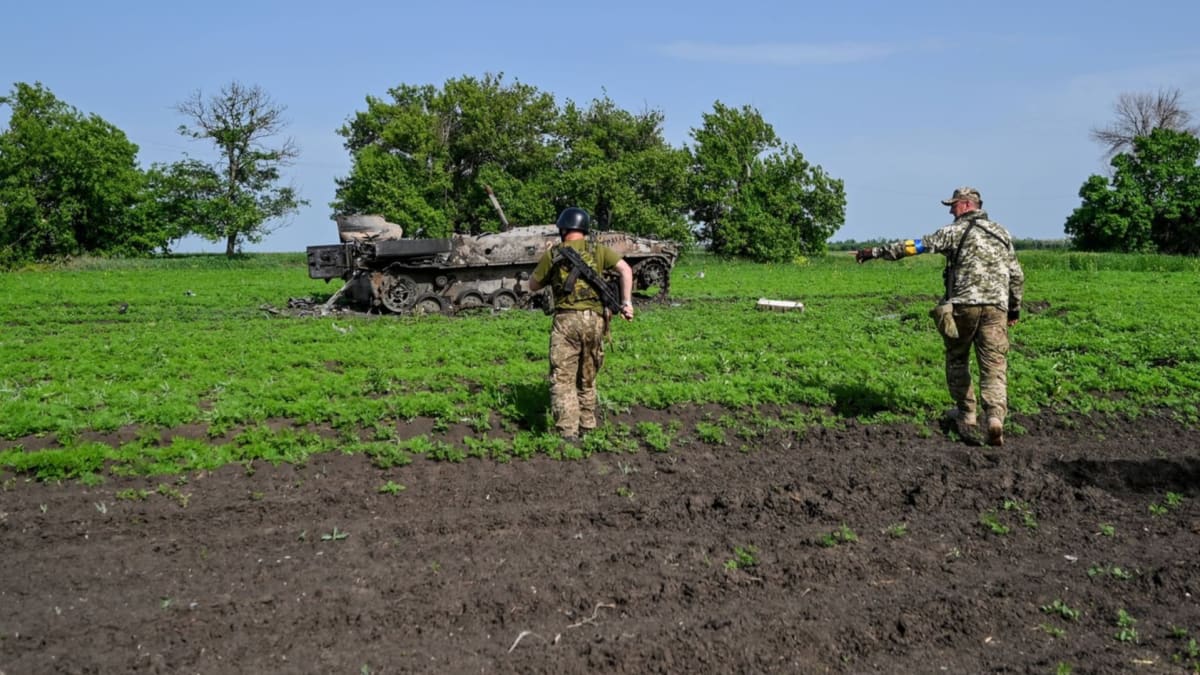 Ukrajinští vojáci stojí u zničeného ruského obrněnce. (31. května)
