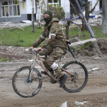 Proruský separatista z Doněcké lidové republiky jede na kole zničenými ulicemi Mariupolu. (4. květen)
