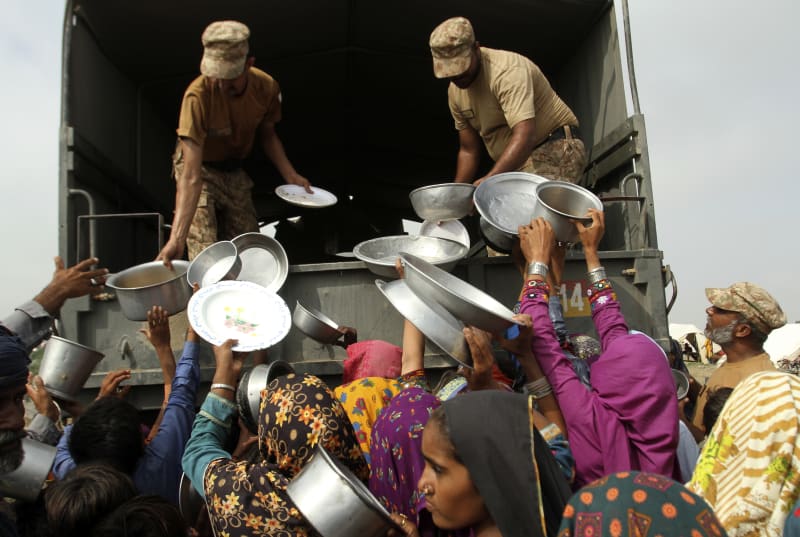 Lidé stojí v dlouhé frontě s nádobím na jídlo, které rozdávají jednotky pákistánské armády. (27. 8. 2022)
