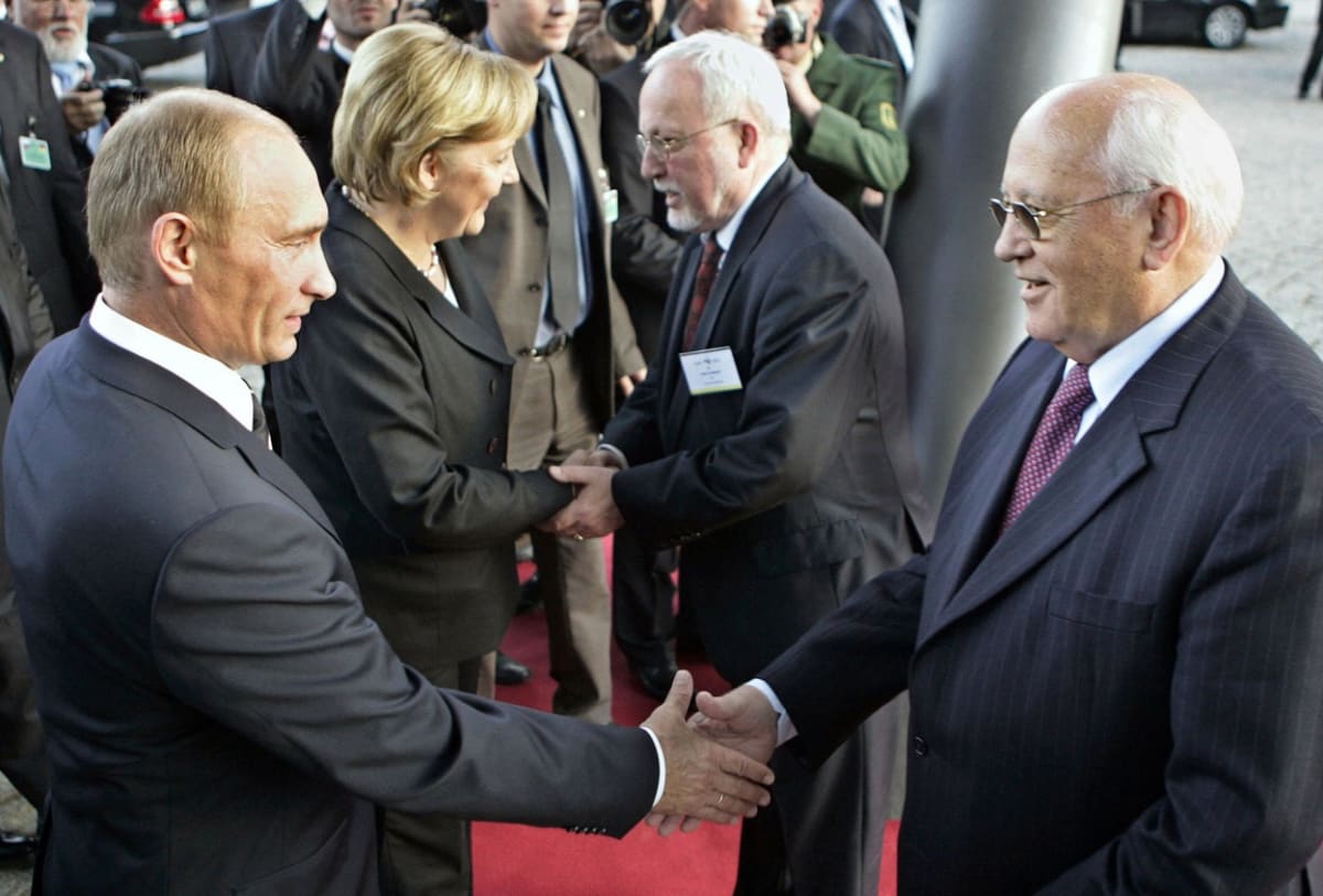 Ruský prezident Vladimir Putin (vlevo) si potřásá rukou s posledním vládcem SSSR Michailem Gorbačovem (vpravo). V pozadí bývalá německá kancléřka Angela Merkelová v rozhovoru s posledním lídrem samostatné Německé demokratické republiky Lotharem de Maizi...
