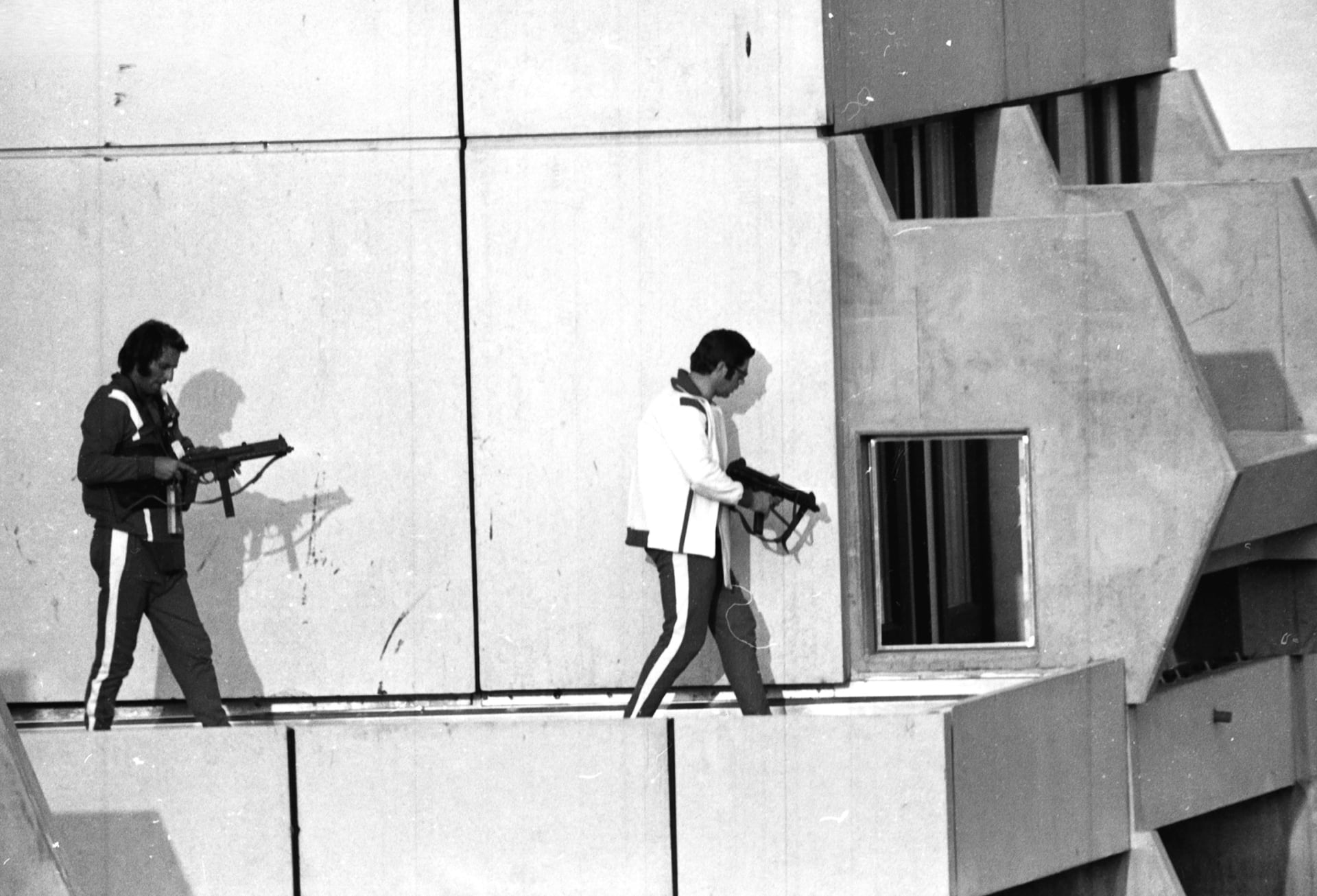 Dva západoněmečtí policisté ozbrojení samopaly a oblečení do teplákových souprav obsazují střechu budovy, kde ozbrojení palestinští teroristé drží jako rukojmí členy izraelského olympijského týmu při Hrách 1972 v Mnichově.