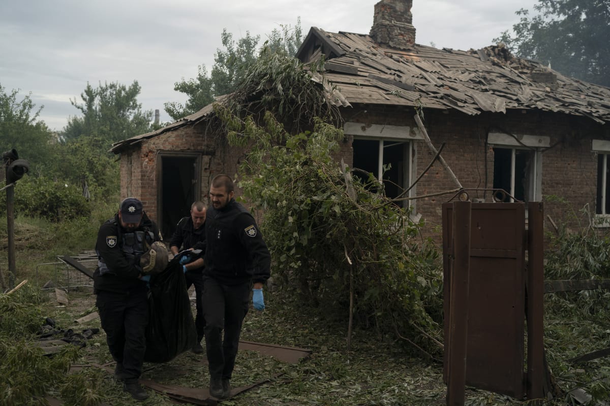 Policisté vynáší tělo zabitého civilisty po ruském útoku u města Pokrovsk v Doněcké oblasti