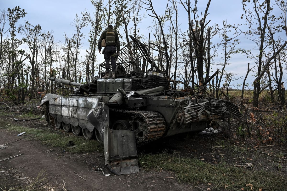 Ukrajinský voják stojí na opuštěném ruském tanku poblíž města Izjum.