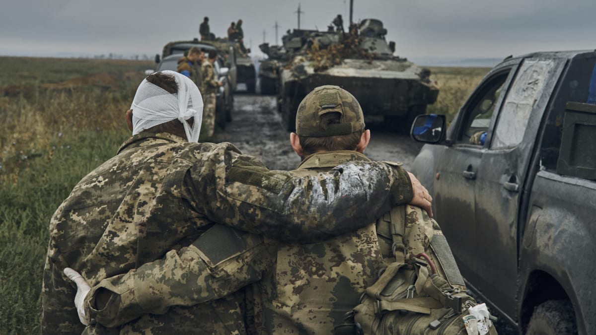Ukrajinský voják pomáhá zraněnému kolegovi během ofenzivy v Charkovské oblasti