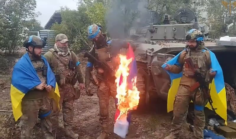 Ukrajinští vojáci pálí ruskou vlajku v osvobozeném městě Volčansk v Charkovské oblasti.