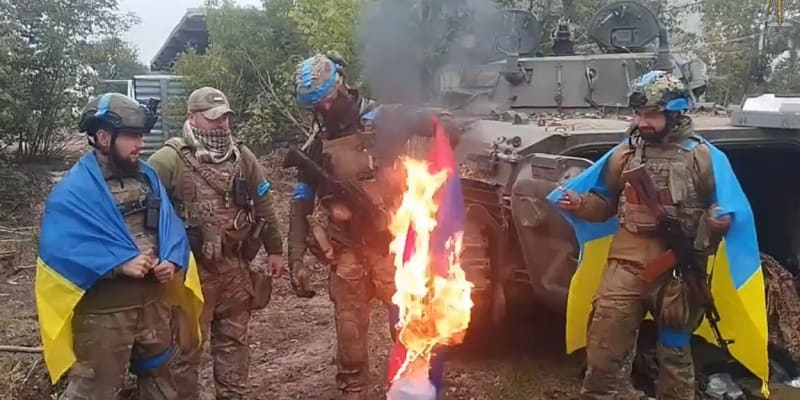 Ukrajinští vojáci pálí ruskou vlajku v osvobozeném městě Volčansk v Charkovské oblasti