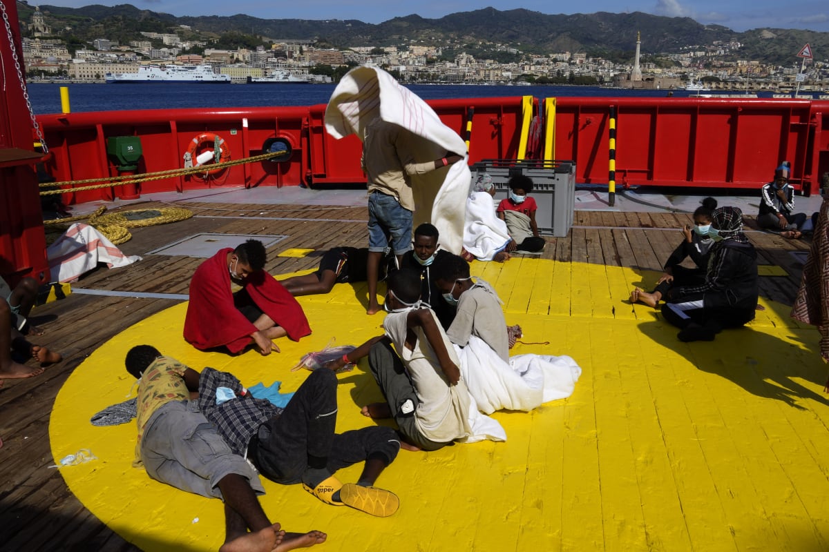 Migranti sedí na palubě záchranné lodi španělské nevládní organizace Open Arms po zakotvení v přístavu Messina na italské Sicílii ve čtvrtek 22. září 2022. 