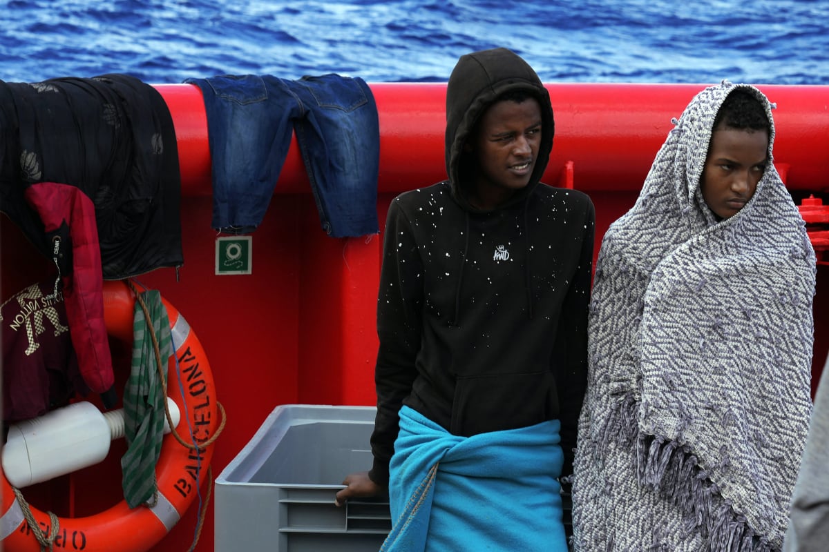 Dva migranti stojí na palubě záchranné lodi španělské nevládní organizace Open Arms poté, co byli zachráněni z otevřených vod během záchranné operace v mezinárodní vodní zóně Středozemního moře, středa 21. září 2022.