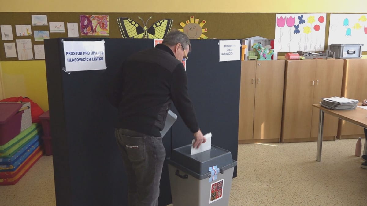 Muž vhazuje lístek do volební urny.