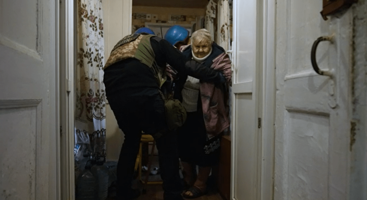 Ukrajinští záchranáři evakuují důchodkyni ze zasaženého města Toreck v Doněcké oblasti.