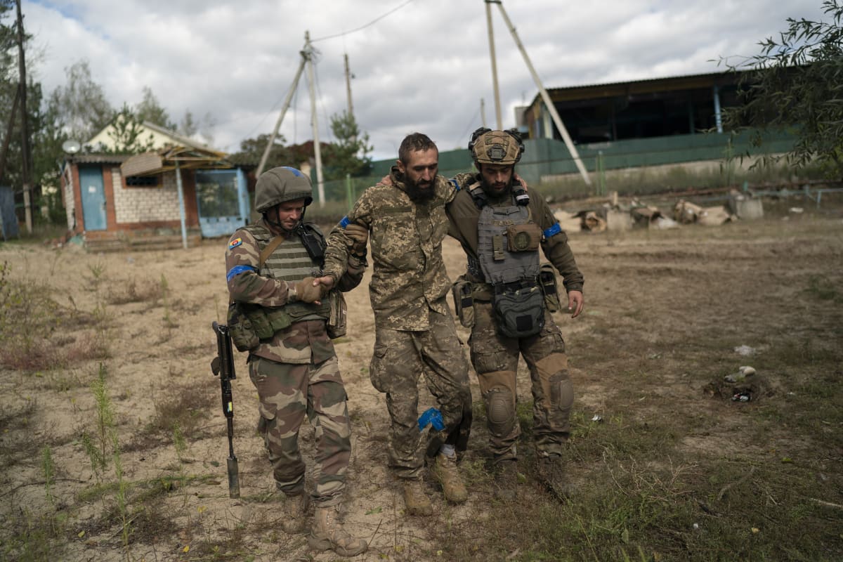 Ukrajinští vojáci pomáhají zraněnému kolegovi u znovudobyté obce Ščurove v Doněcké oblasti