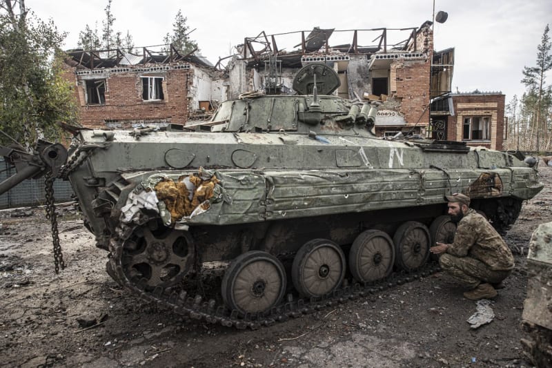 Ukrajinský voják u ruského obrněného vozidla, které okupanti zanechali během ústupu v ulicích Izjumu.