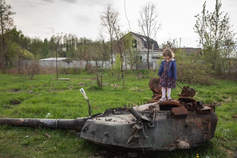 Dítě stojí na vraku ruského tanku.