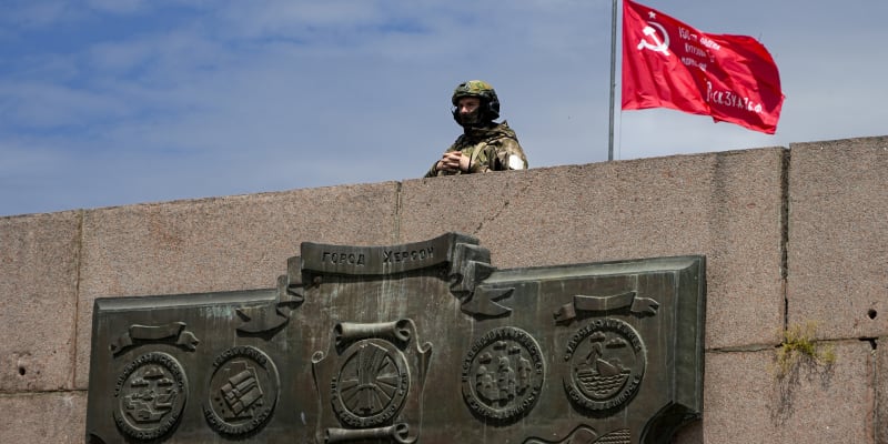 Ruský voják u Chersonu pózuje u vlajky se srpem a kladivem.