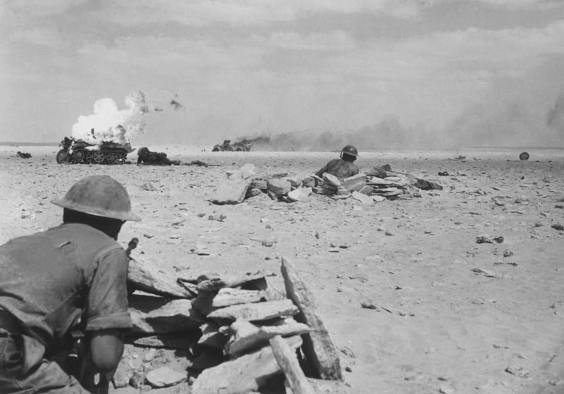 Britští vojáci se plíží k hořícím německým vozidlům
