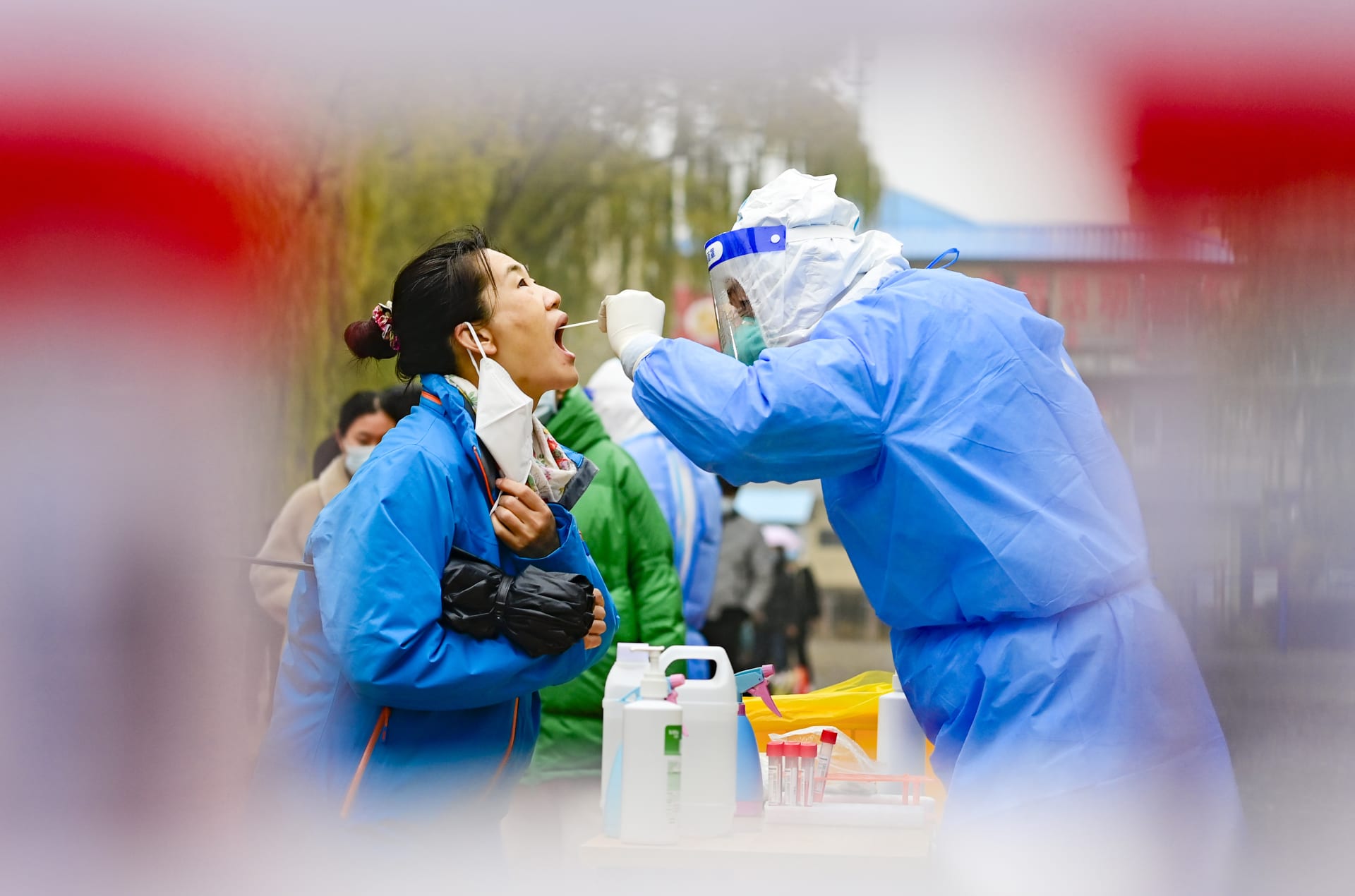 Zdravotnický pracovník provádí odběr vzorků obyvatelům v Hohhotu. Čína, 11. listopadu 2022. 