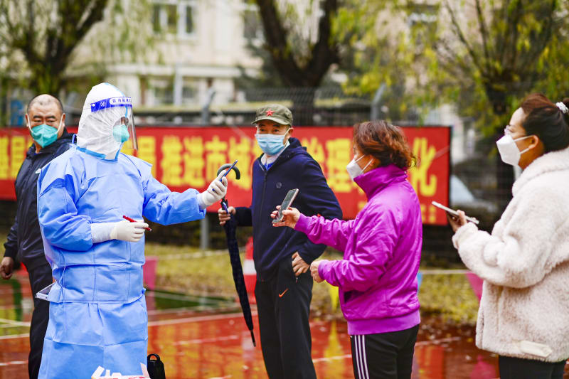Zdravotnický pracovník provádí odběr vzorků obyvatelům v Hohhotu. Čína, 11. listopadu 2022. 