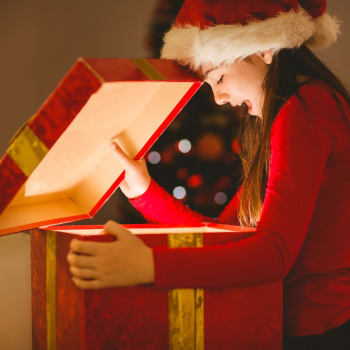 Dívka rozbaluje vánoční dárek. 