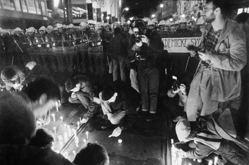 Studenti zapalují svíčky před policejním kordonem.