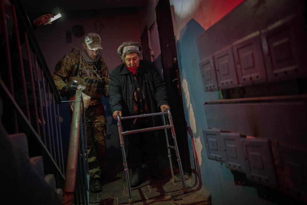 Ukrajinský voják pomáhá seniorce s evakuací z Chersonu. Město je ostřelováno Rusy, je bez energií i vody