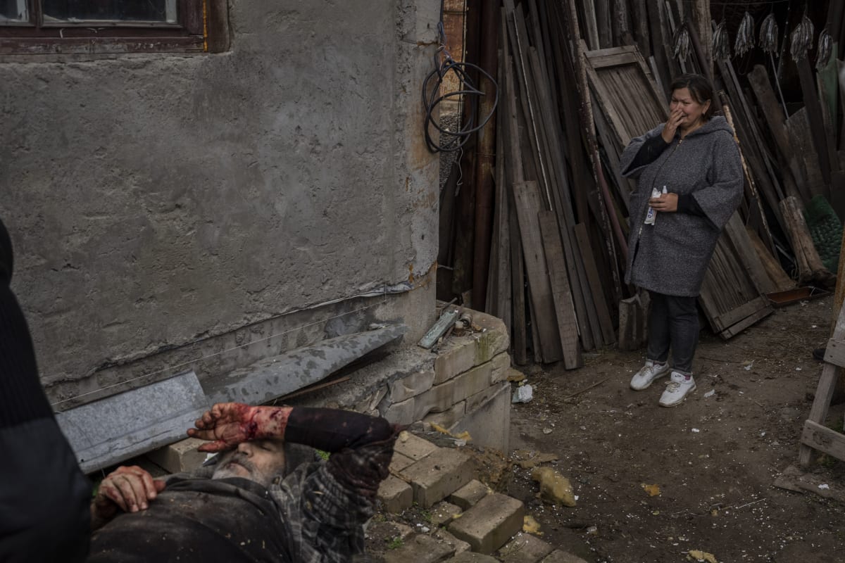 Žena pláče při pohledu na zraněného manžela po ruském útoku na město Cherson