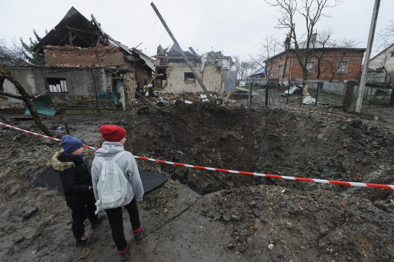 Děti obhlížejí kráter po ruském ostřelování města Solonka ve Lvovské oblasti.