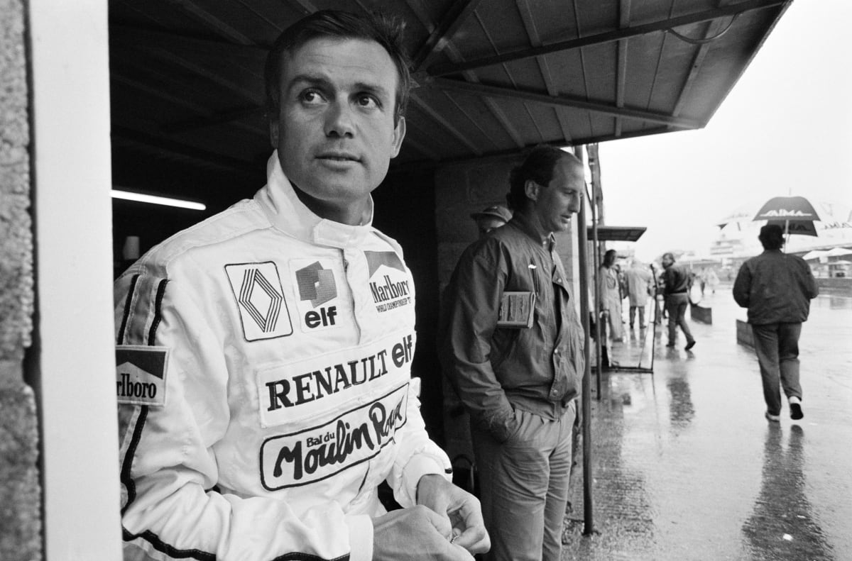 Pilot formule 1 Patrick Tambay, jezdící za Renault, se schovává před deštěm v garáži v boxové uličce během kvalifikace na Velkou cenu Velké Británie 1985 na okruhu Silverstone nedaleko Towcesteru v britském hrabství Northamptonshire v sobotu 20. července 1985. (Foto: Bryn Colton/Getty Images)