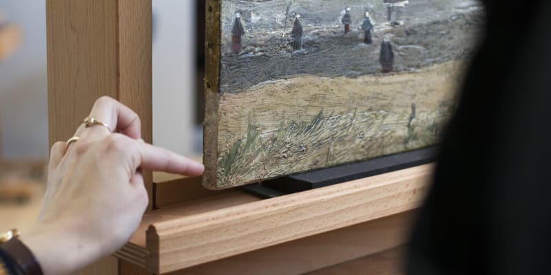 Zaměstnankyně muzea ukazuje na roh malby, který musel být zrestaurován