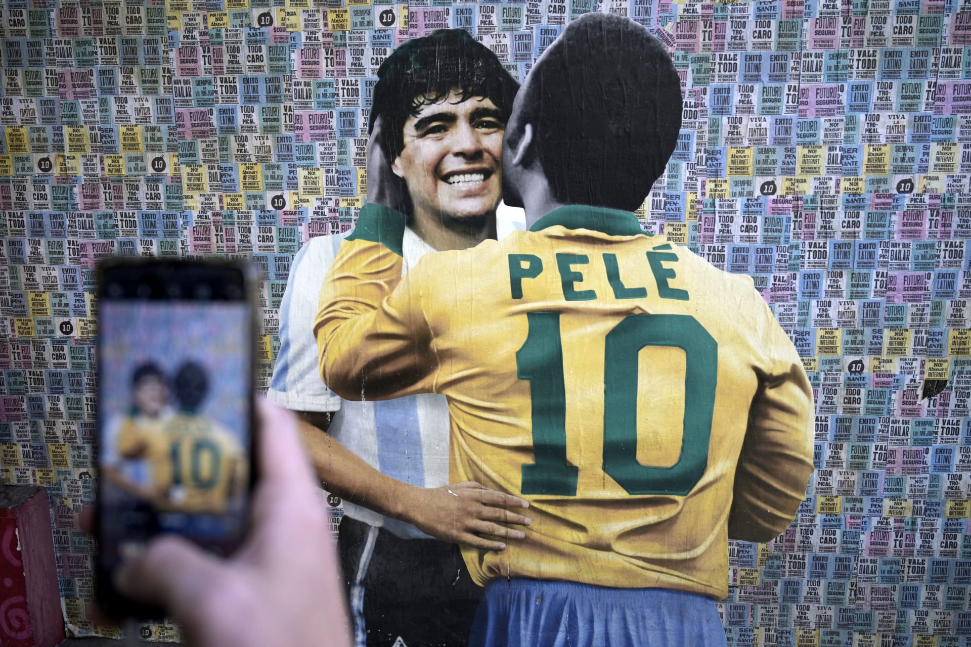 Fanoušek si v Sao Paulu fotí pouliční malbu, na které se objímají Pelé s Diegem Maradonou.