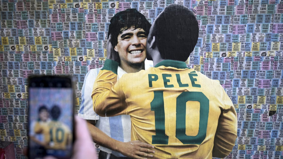 Fanoušek si v Sao Paulu fotí pouliční malbu, na které se objímají Pelé s Diegem Maradonou.