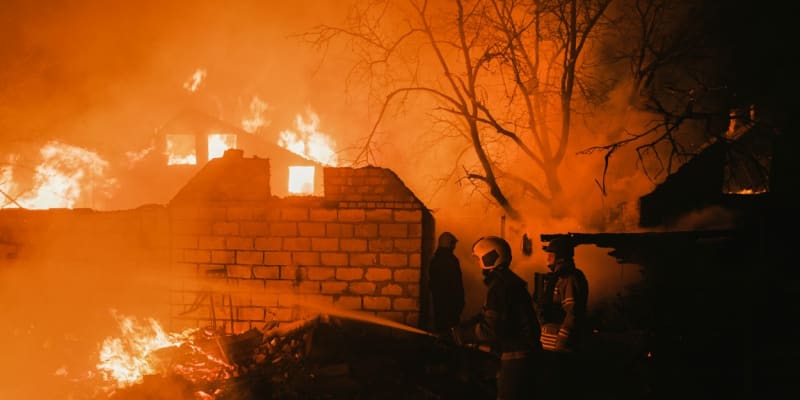Hasiči likvidují požár domu po ruském ostřelování.