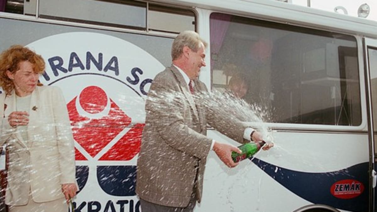 Miloš Zeman právě křtí svůj volební autobus Zemák, salvě šampaňského uhýbá Petra Buzková. 