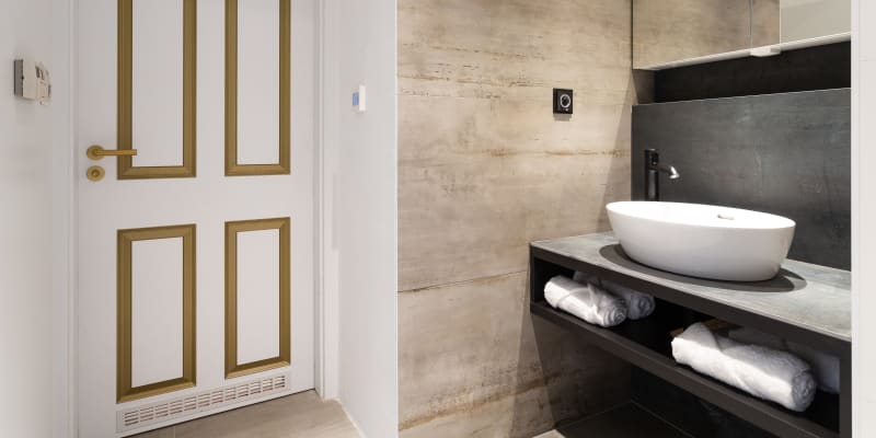 Jak se staví sen: Koupelna zaznamenala více změn. Ta je zcela přepracovaná, je laděna do bílých, šedých a černých odstínů v kombinaci s černými a zlatými doplňky.
