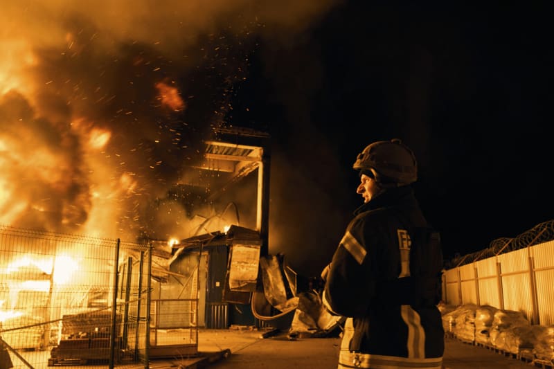 Ukrajinští hasiči likvidují požár po ruském bombardování.