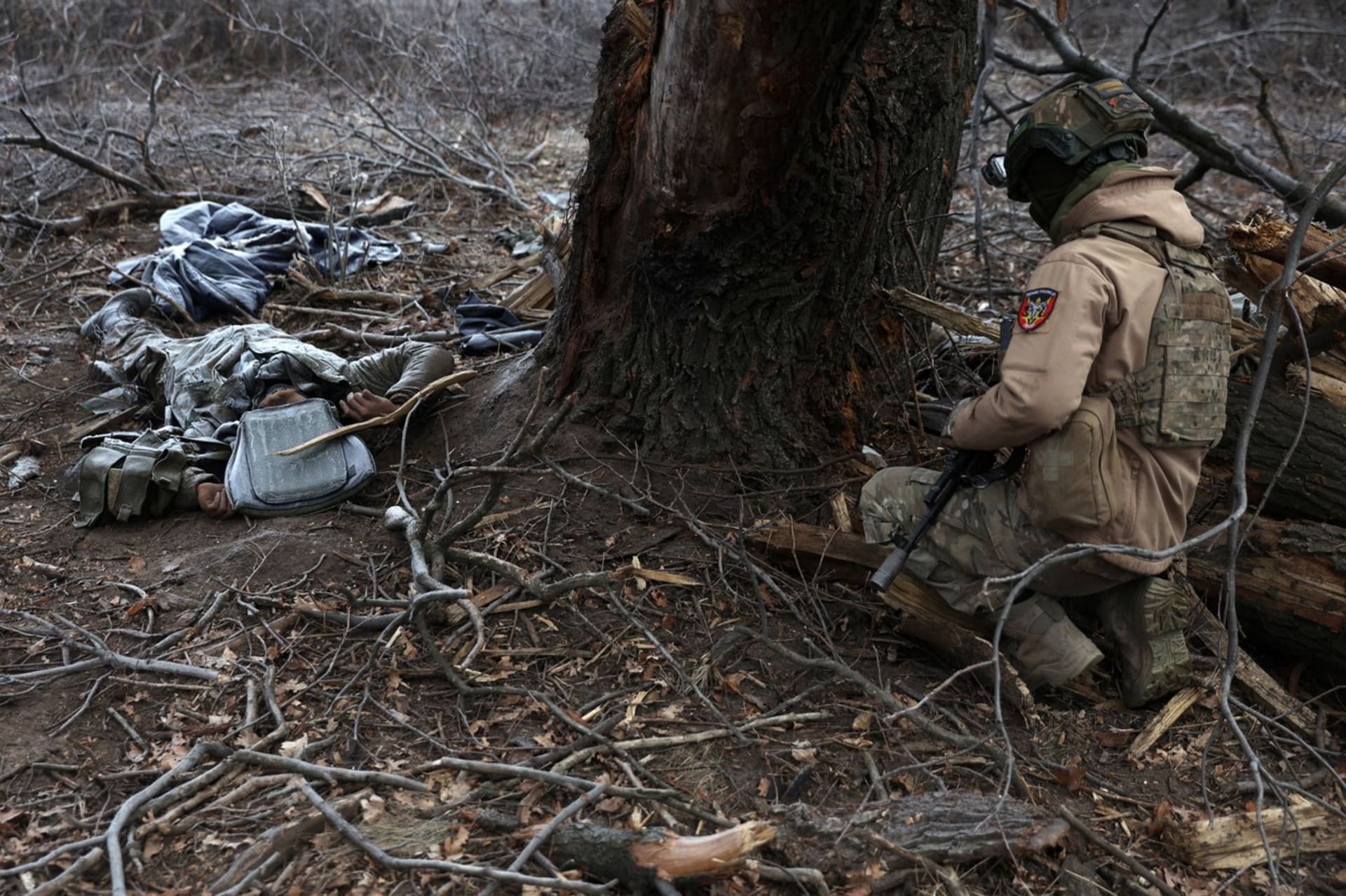 Ukrajinský voják klečí u mrtvých ruských okupantů.