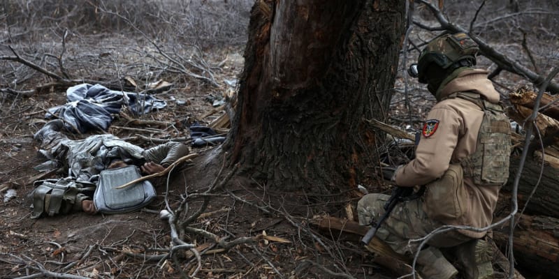 Ukrajinský voják klečí u mrtvých ruských okupantů.