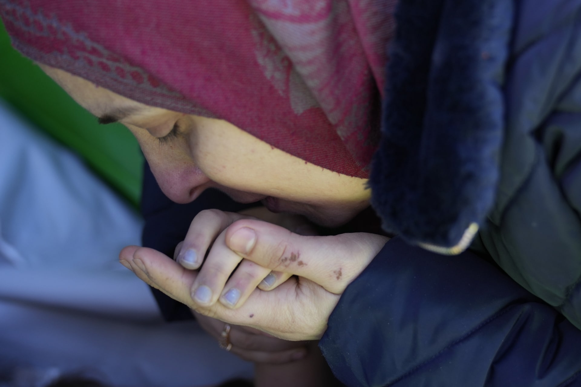 Matka ze Sýrie líbá ruku své mrtvé dceři, která se stala obětí zemětřesení a bude převezena do Sýrie k pohřbu, z tureckého přechodu Cilvegozu v Reyhanli na jihovýchodě Turecka, čtvrtek 9. února 2023. 