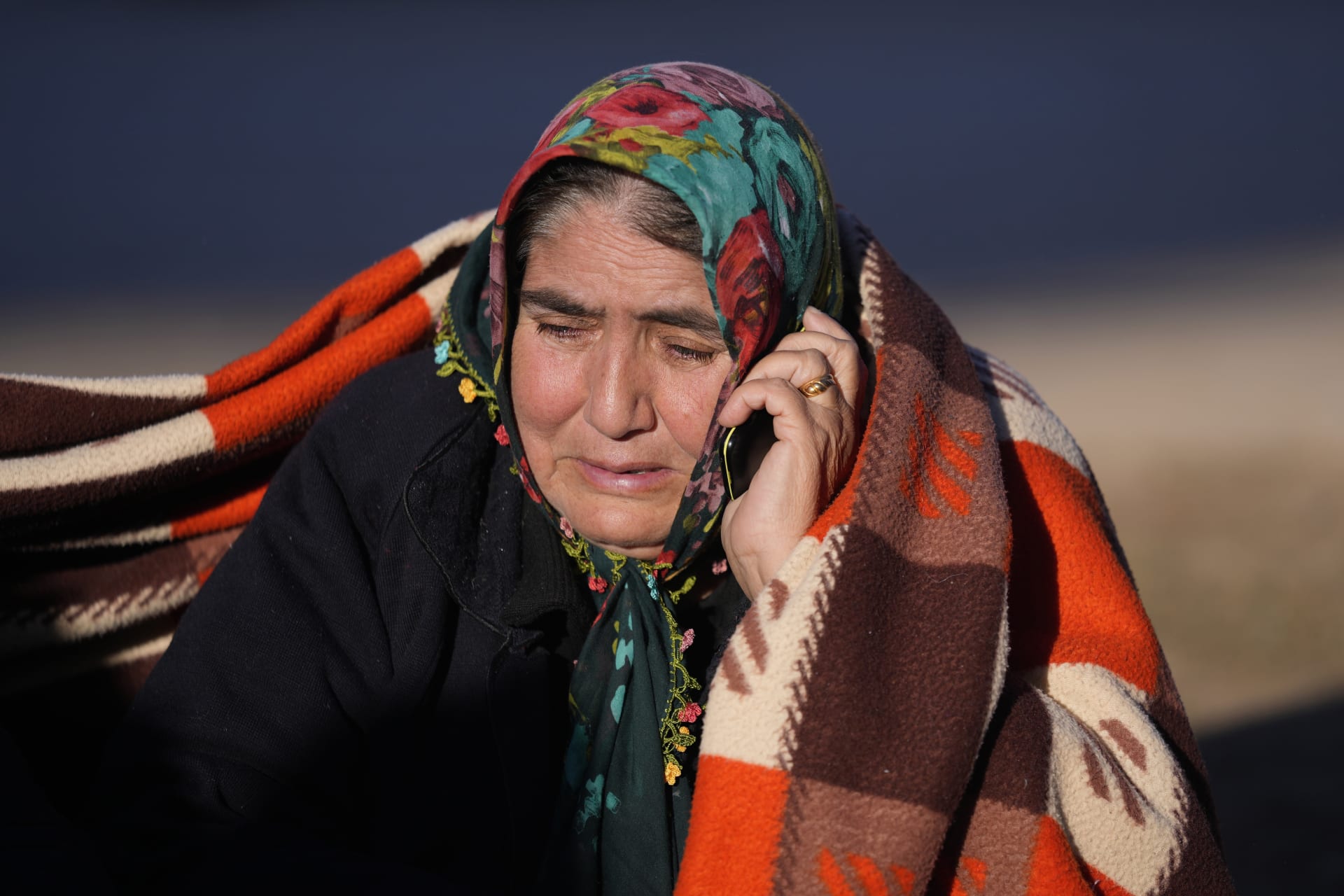 Žena mluví do mobilního telefonu, zatímco záchranáři prohledávají zničenou budovu v Gaziantepu na jihovýchodě Turecka, čtvrtek 9. února 2023. 