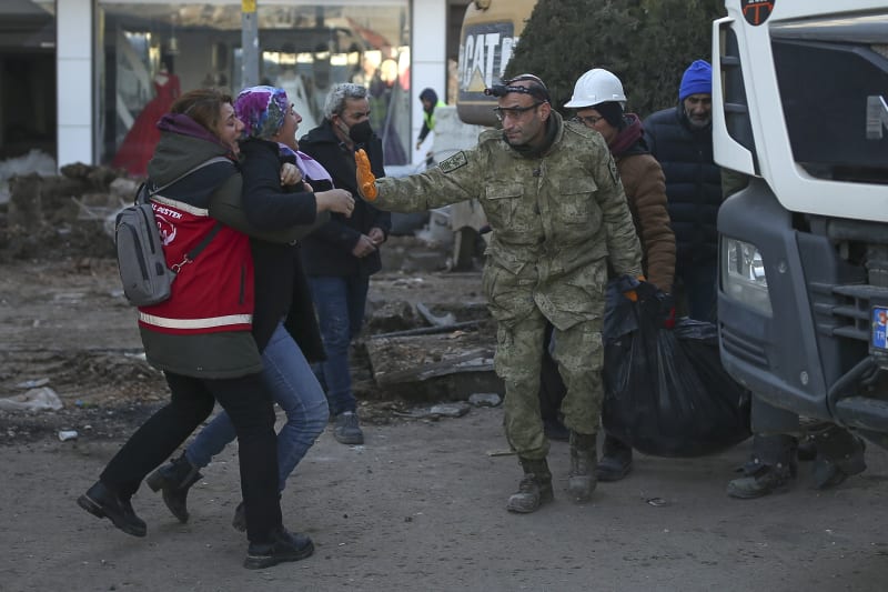 Žena reaguje, když záchranáři odnášejí tělo oběti zemětřesení v Adiyamanu na jihovýchodě Turecka, čtvrtek 9. února 2023. 