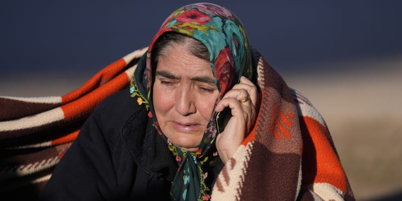 Žena mluví do mobilního telefonu, zatímco záchranáři prohledávají zničenou budovu v Gaziantepu na jihovýchodě Turecka, čtvrtek 9. února 2023. 