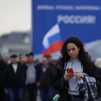 Lidé s ruskými vlajkami se shromažďují na Rudém náměstí během slavnostního ceremoniálu u příležitosti anexe čtyř ukrajinských regionů po referendu 30. září 2022 v Moskvě.