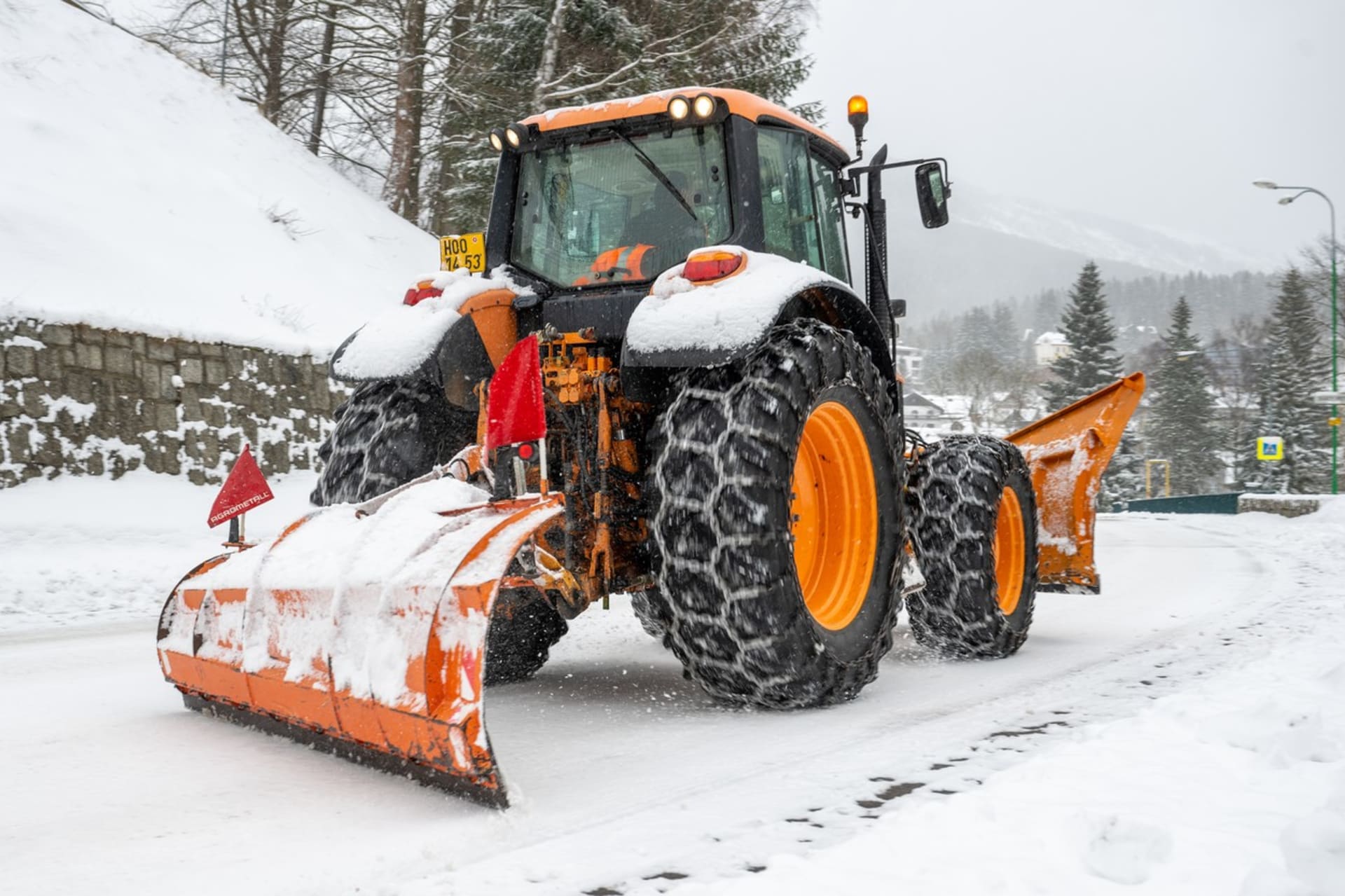 Traktor odklízí sníh ze silnice v centru Špindlerova Mlýna.